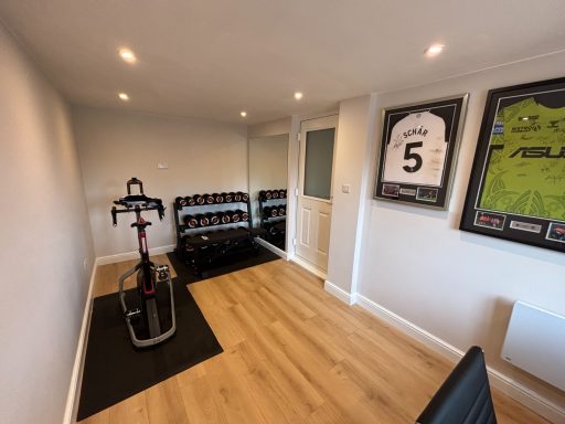 Converted garage to gym Modern indoor fitness room featuring exercise equipment and framed sports jerseys.