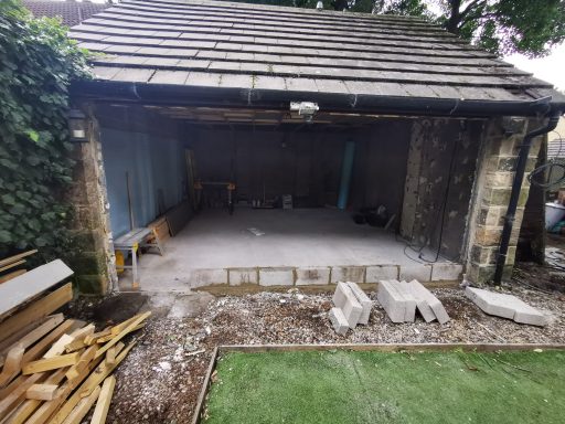 A partially constructed garage with some building materials outside.