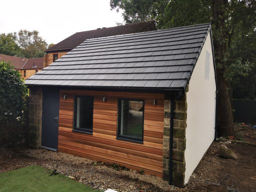 A modern single-storey building with wooden cladding and a slate roof.