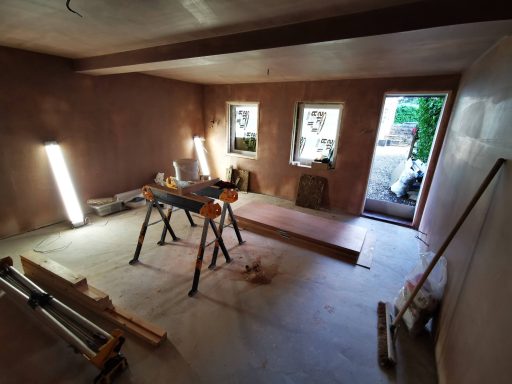 Interior of a partially renovated room with tools and wooden beams on the floor.