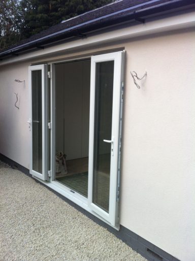 White exterior of a building with double French doors, a small dog visible inside.