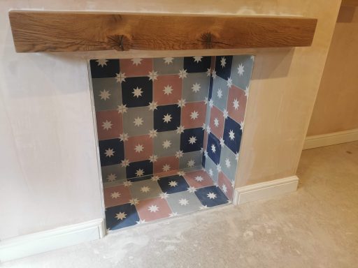 A decorative fireplace with patterned tiles and a wooden mantel.