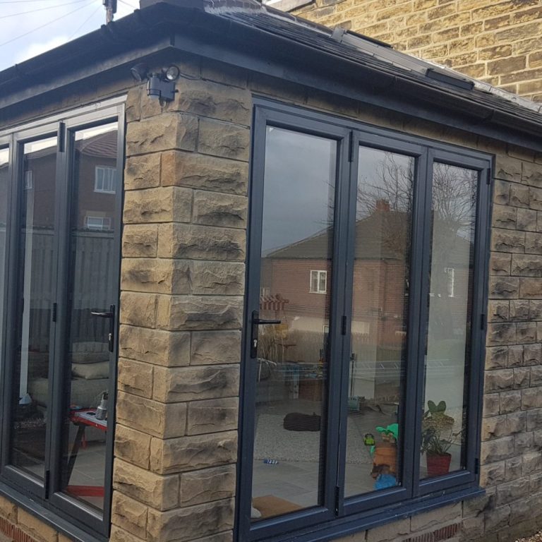 A modern conservatory with large glass windows and a stone exterior.