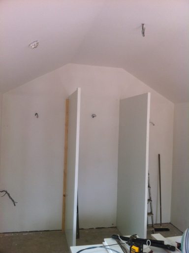 Interior of an unfinished room with white walls and two partition walls.