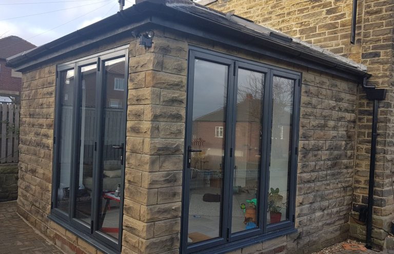 Modern extension of a house with large windows and a stone exterior.