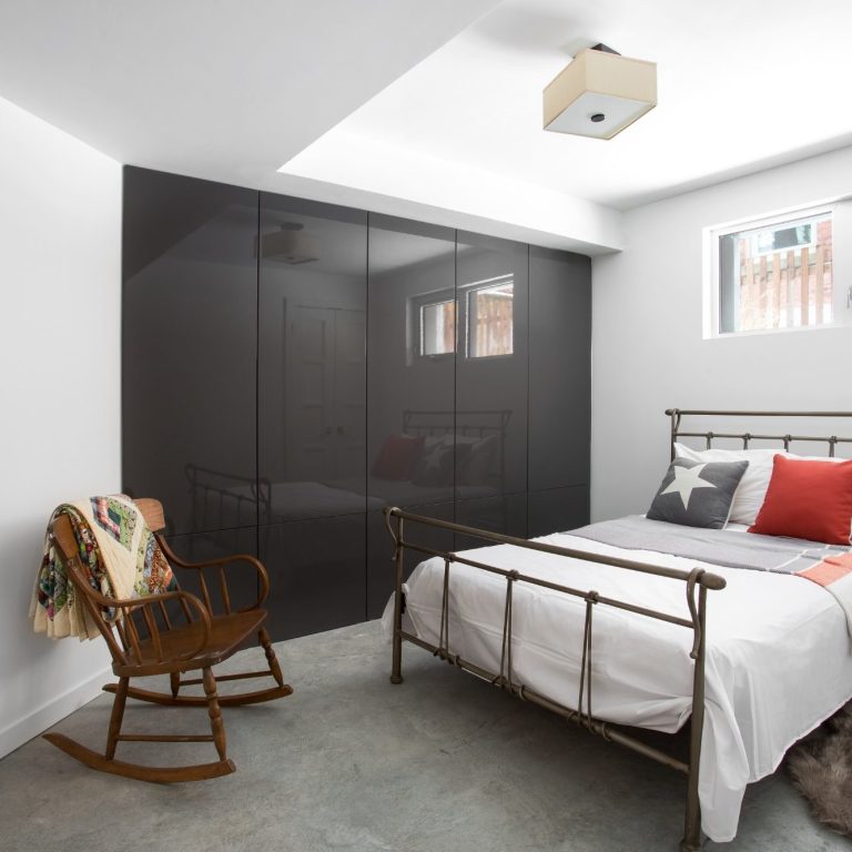 Modern bedroom with a metal bed, rocking chair, and sleek black wardrobe in a basement/cellar