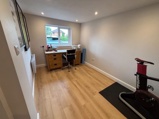 Converted garage A spacious, well-lit room with a desk, chair, and exercise bike against a light wall.