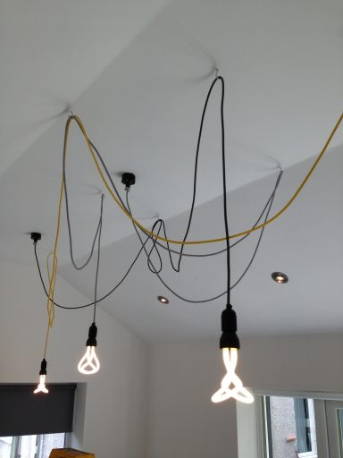 Three hanging light bulbs with exposed cables in a modern room.