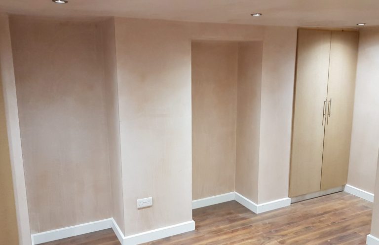 Minimalist interior space with light beige walls and wooden flooring, featuring a closet.