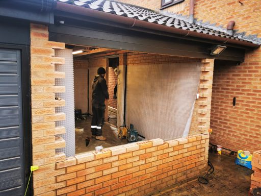 Construction work in progress on a house extension with brick walls and a partially completed interior.